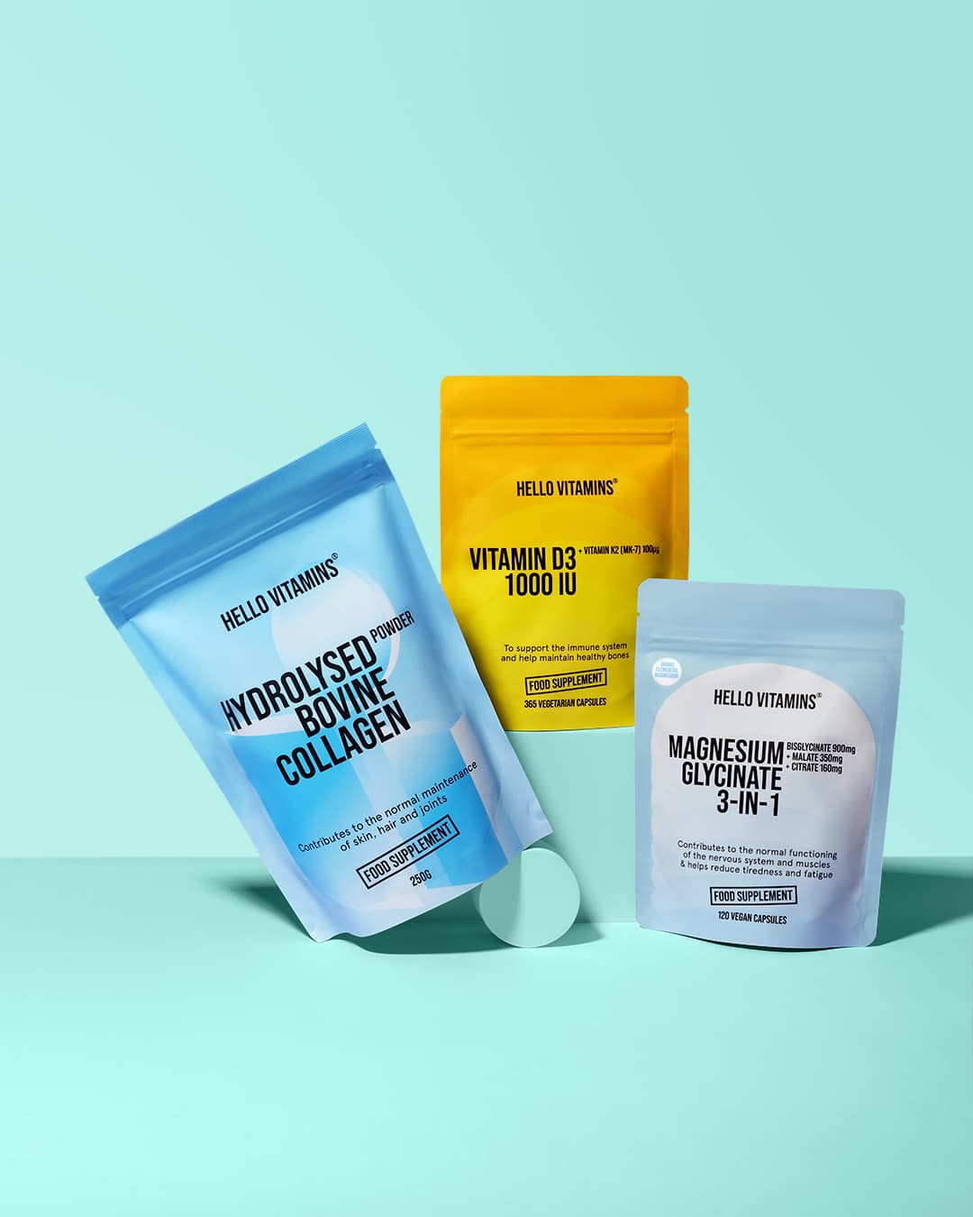 Three Hello Vitamin supplement pouches arranged on pale green blocks